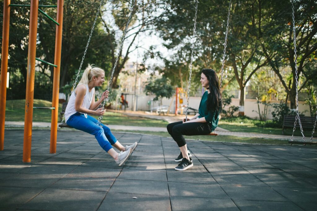 two women chatting on swings