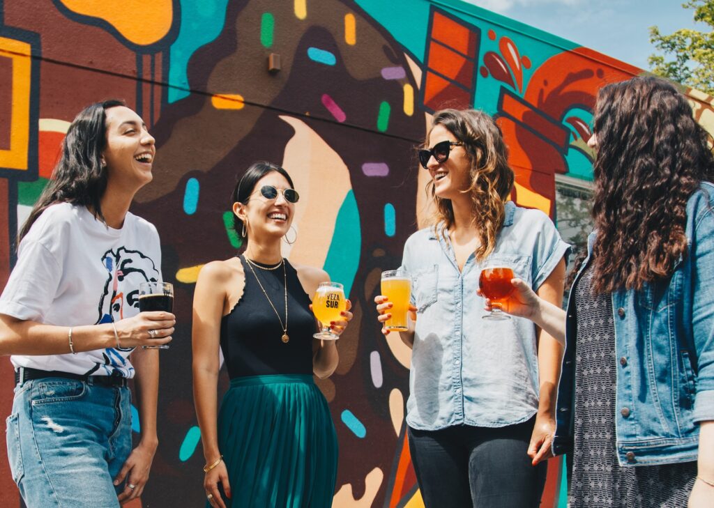 female friends enjoying drinks by graffiti wall