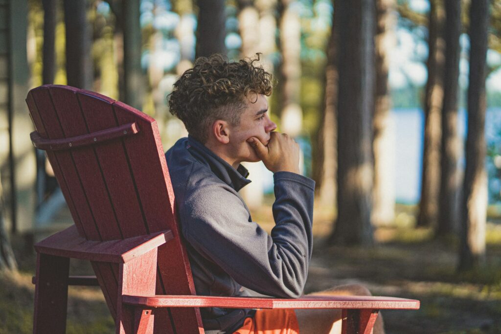 guy sitting outside in woods looking thoughtful