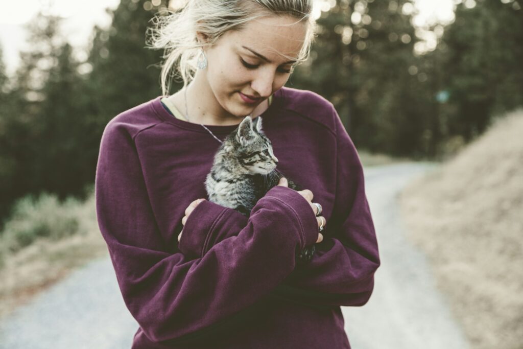 woman cuddling kitten outside