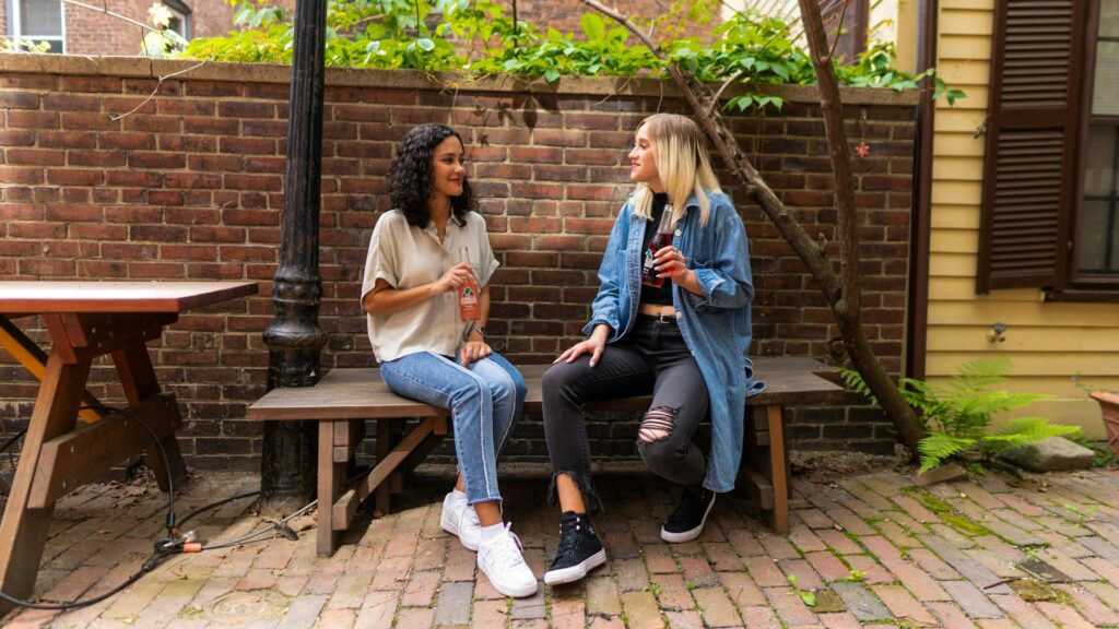 two women chatting on park bench outdoors