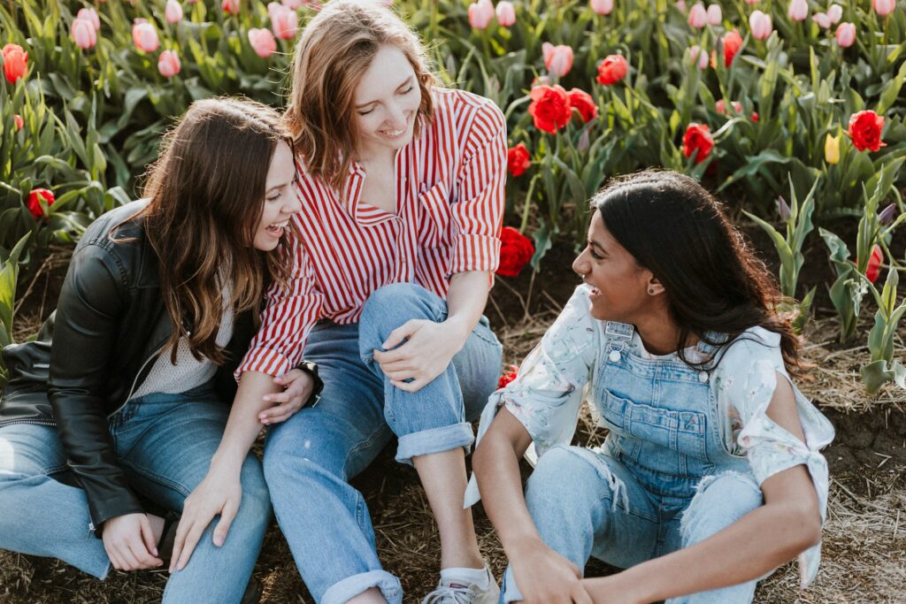 three female friends chatting in field of flowers