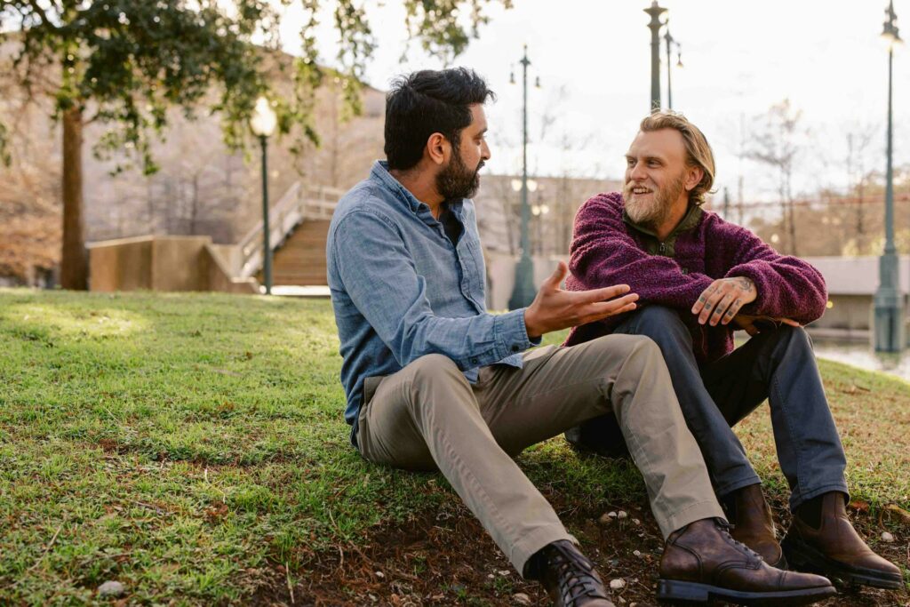 two men talking on grass